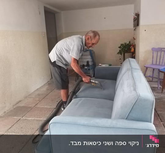 אדם מנקה ספה עם שואב אבק